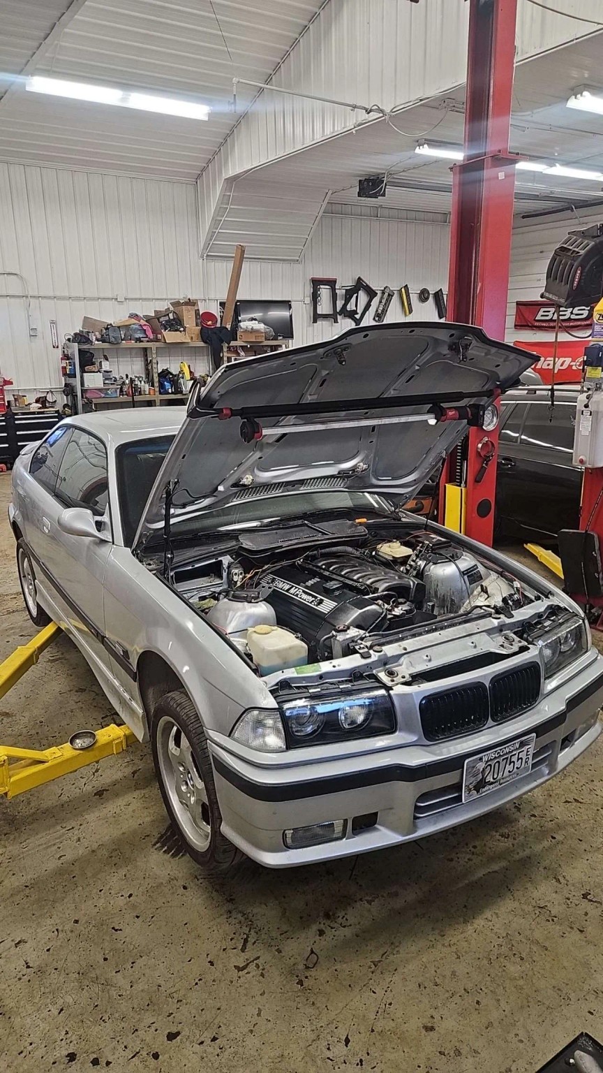 Silver BMW in the auto shop with the hood open