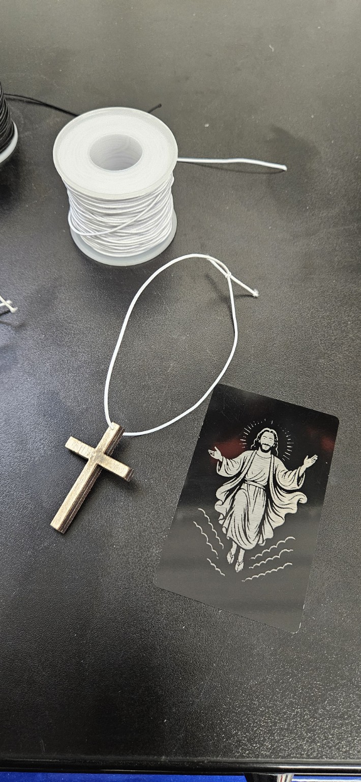 Engraved prayer card beside a handmade wooden cross
